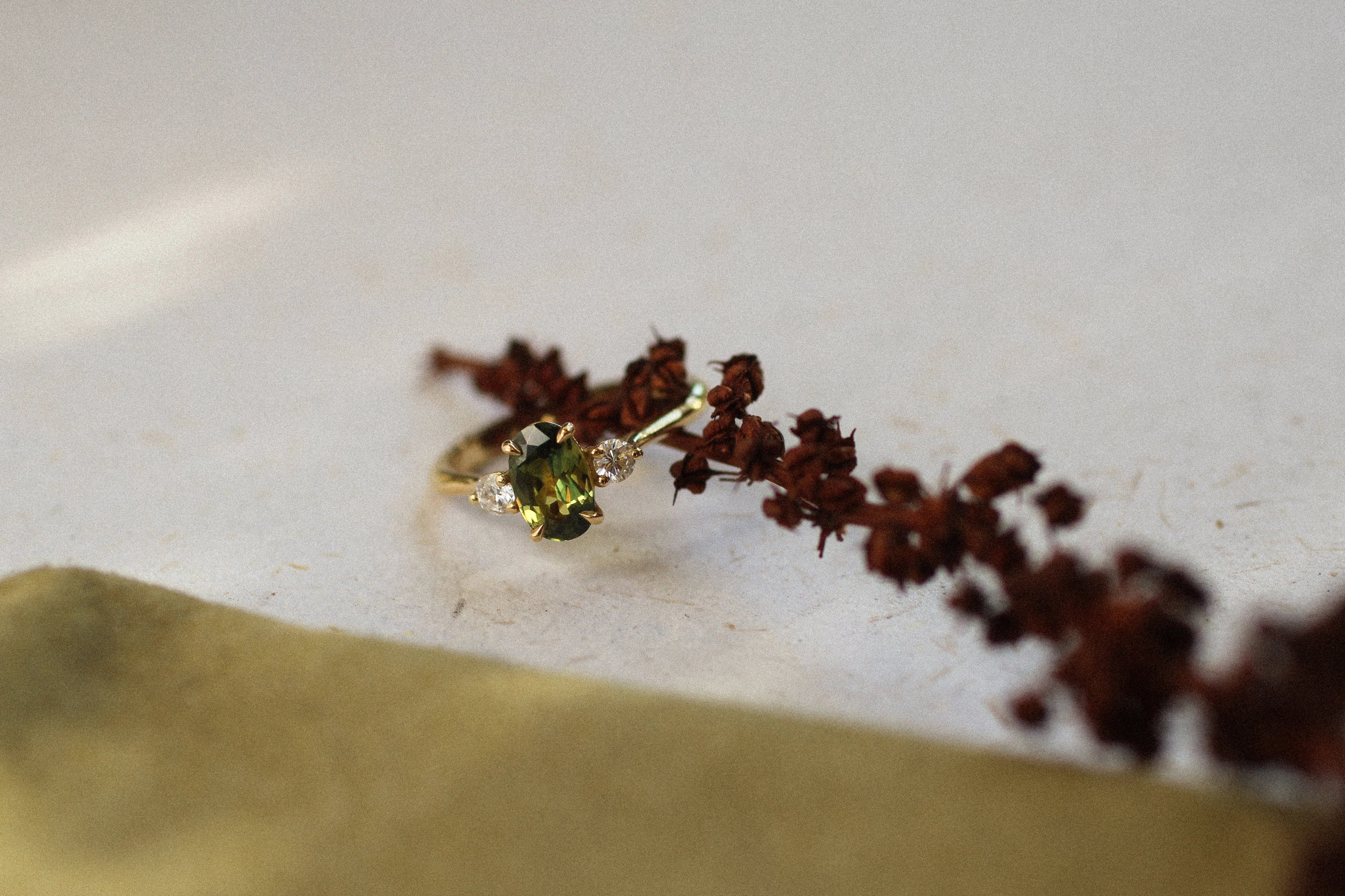 trilogy engagement ring with green sapphire on branch