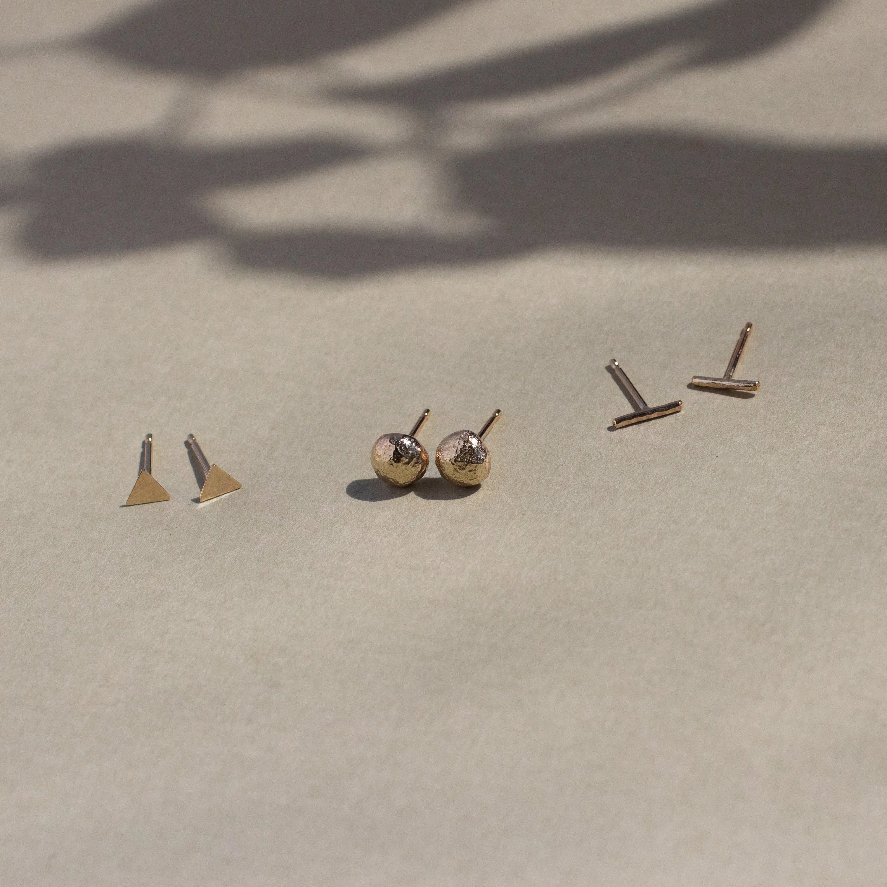 three pairs of gold stud earrings in jewellery set with leaf shadow