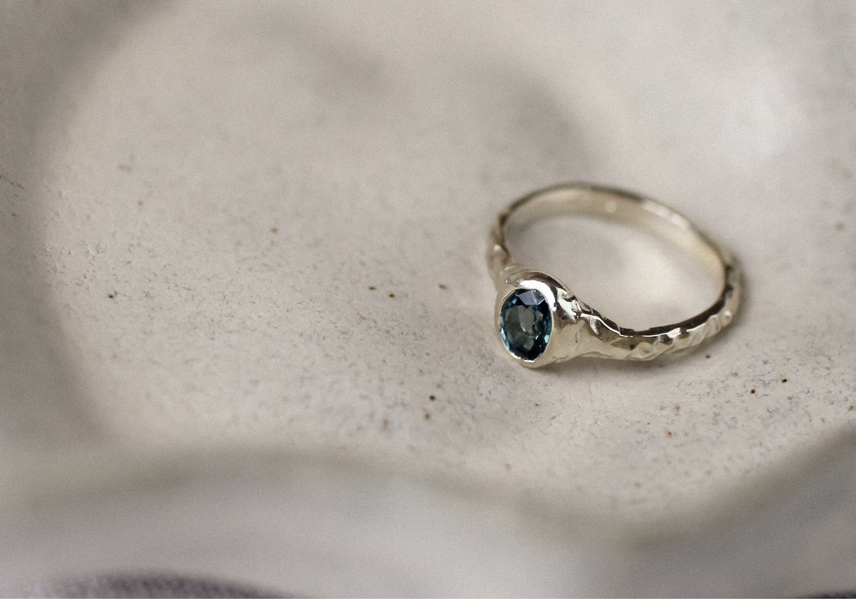 white gold engagement ring with a blue sapphire on a eramic dish