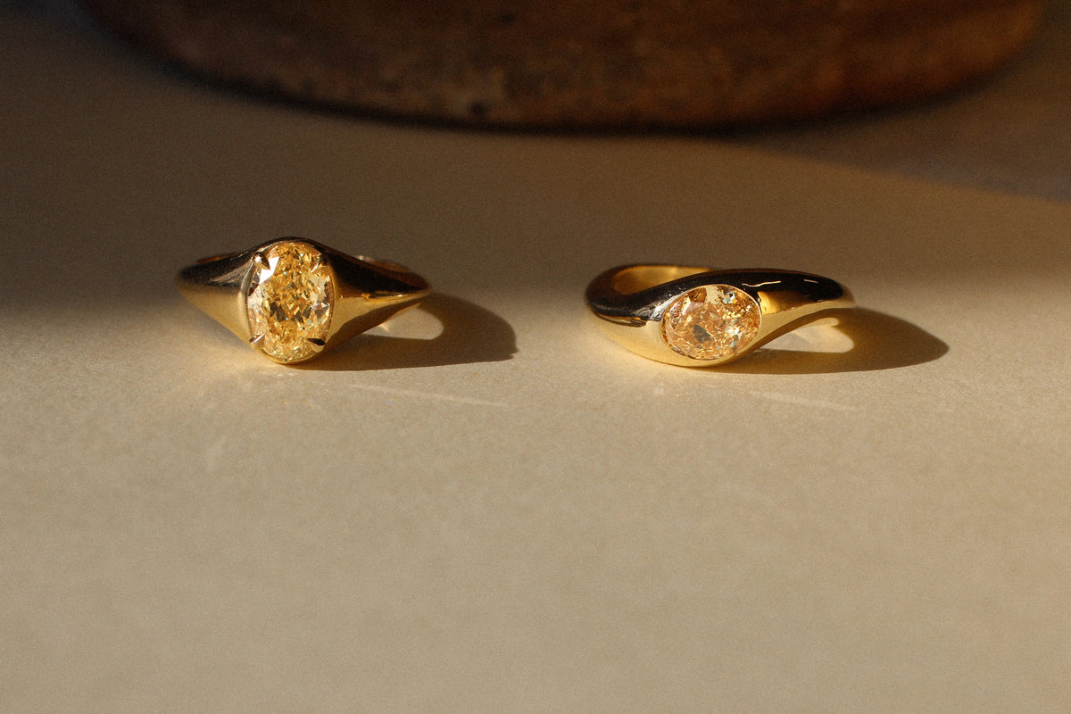 two yellow diamond engagement rings with shadow featuring oval yellow diamonds with bezel and faux bezel settings