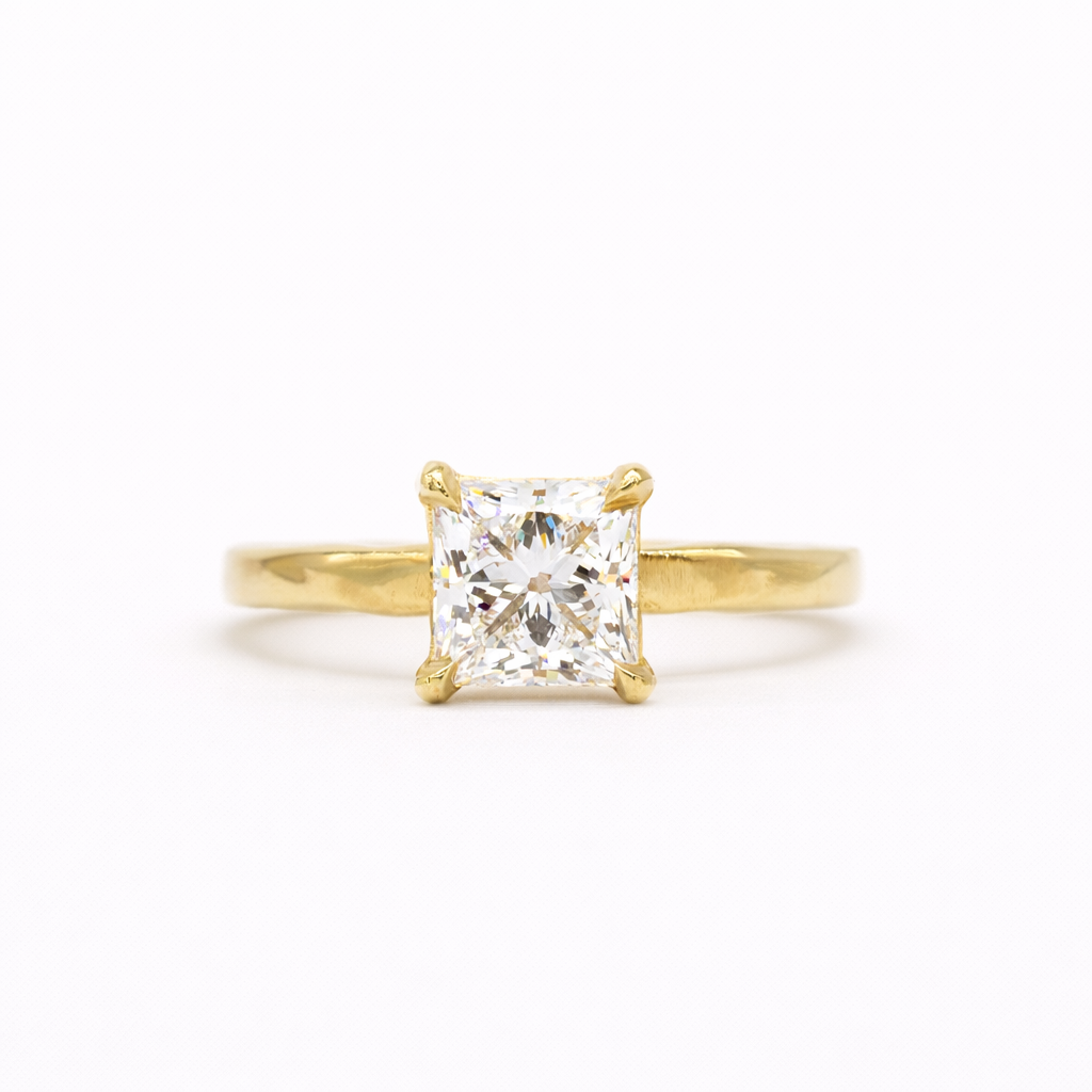 gold engagement ring with square princess cut diamond and textured flat band on a white background