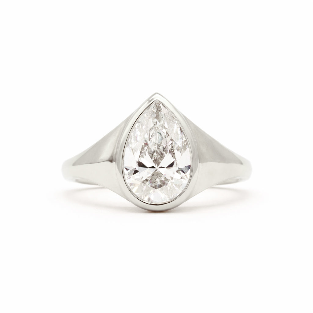 A pear-cut diamond ring set in a polished silver-colored metal band, shown against a plain white background.