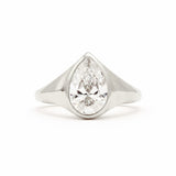 A pear-cut diamond ring set in a polished silver-colored metal band, shown against a plain white background.