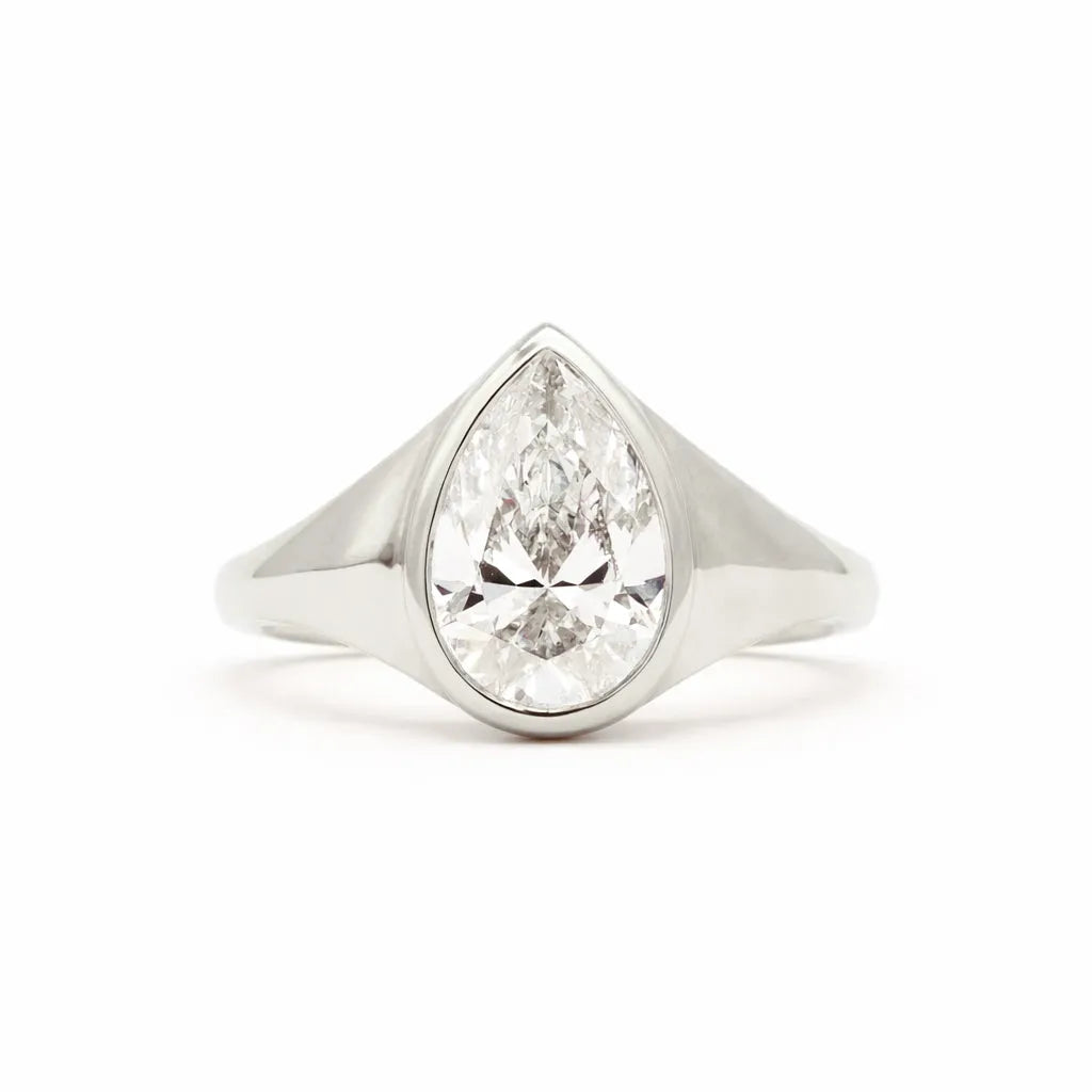 A pear-cut diamond ring set in a polished silver-colored metal band, shown against a plain white background.