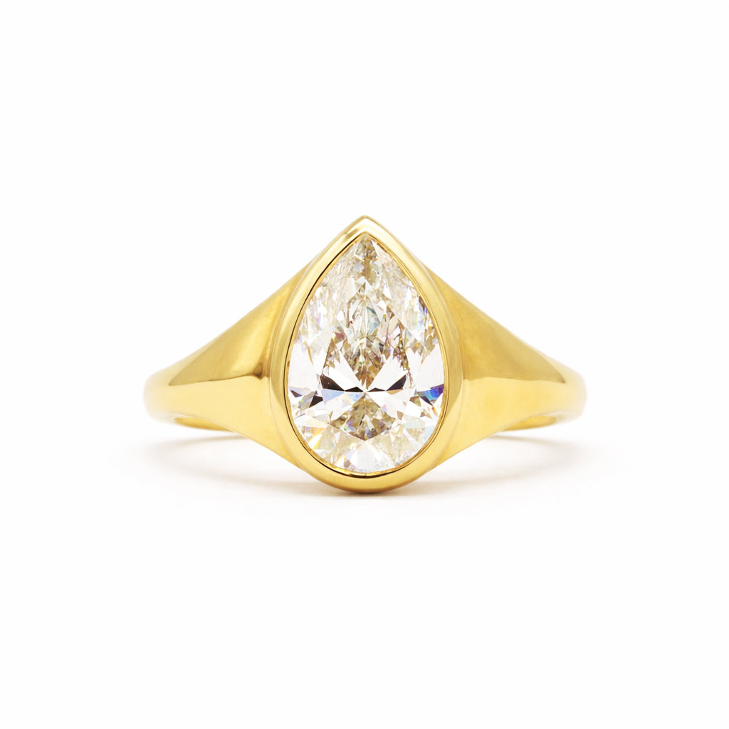 A yellow gold ring featuring a large pear-cut clear gemstone in a prong setting, shown against a plain white background.