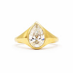 A yellow gold ring featuring a large pear-cut clear gemstone in a prong setting, shown against a plain white background.