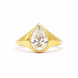 A yellow gold ring featuring a large pear-cut clear gemstone in a prong setting, shown against a plain white background.