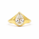 large bezel set pear diamond engagement ring on a white background