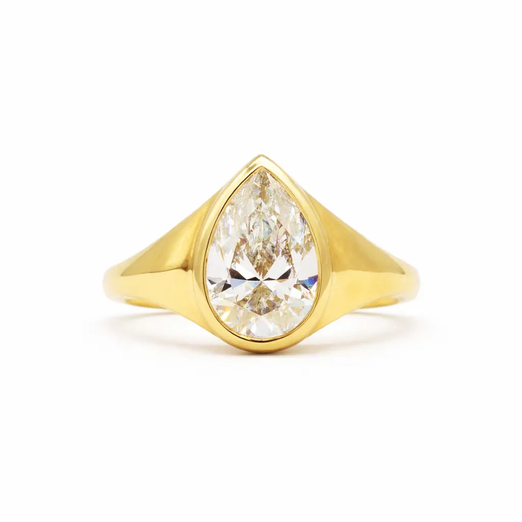 large bezel set pear diamond engagement ring on a white background