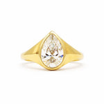 A yellow gold ring featuring a large pear-cut clear gemstone in a prong setting, shown against a plain white background.