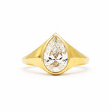 A yellow gold ring featuring a large pear-cut clear gemstone in a prong setting, shown against a plain white background.
