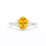 Ring with a yellow gemstone and diamond accents on a white background