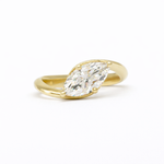 marquise diamond engagement ring with gold waved band on a white background