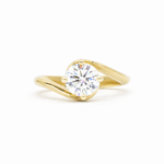 round diamond engagement ring with gold waved band on a white background