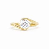 round diamond engagement ring with gold waved band on a white background