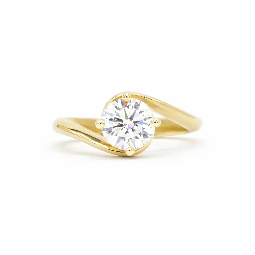 round diamond engagement ring with gold waved band on a white background