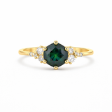 Gold ring with a green gemstone and diamond accents on a white background