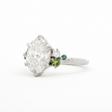 Diamond ring with green gemstones on a white background