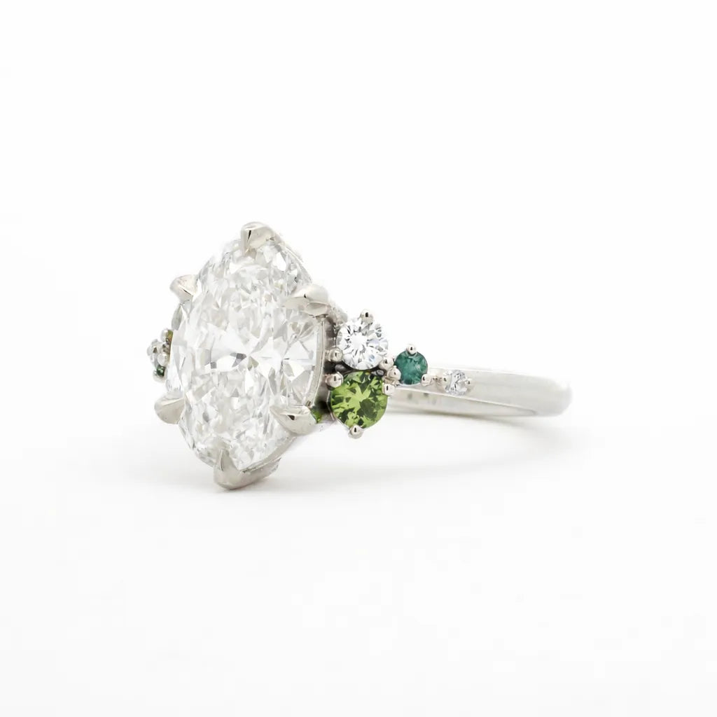 Diamond ring with green gemstones on a white background