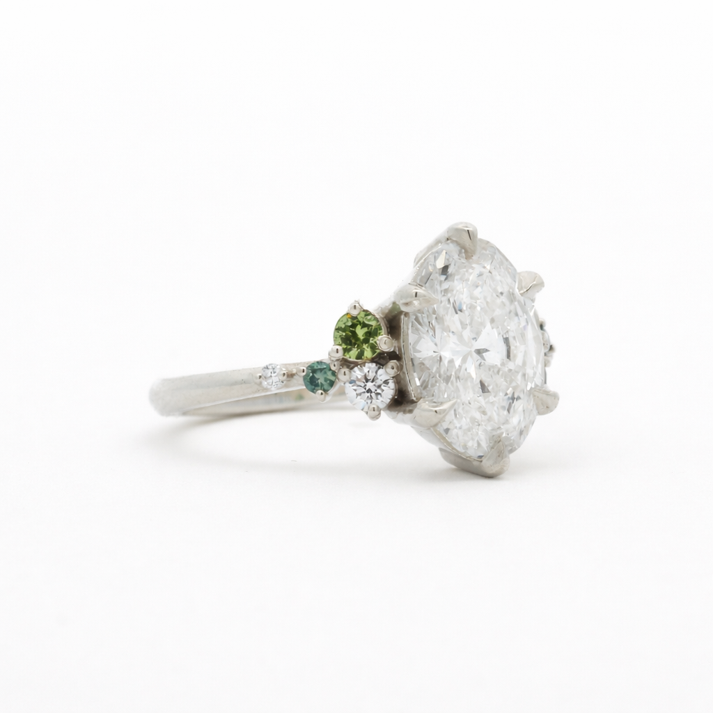 Diamond ring with a green gemstone on a white background