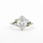 Diamond ring with green gemstones on a white background