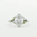 Diamond ring with small green sapphires on a white background