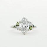 Diamond ring with small green sapphires on a white background