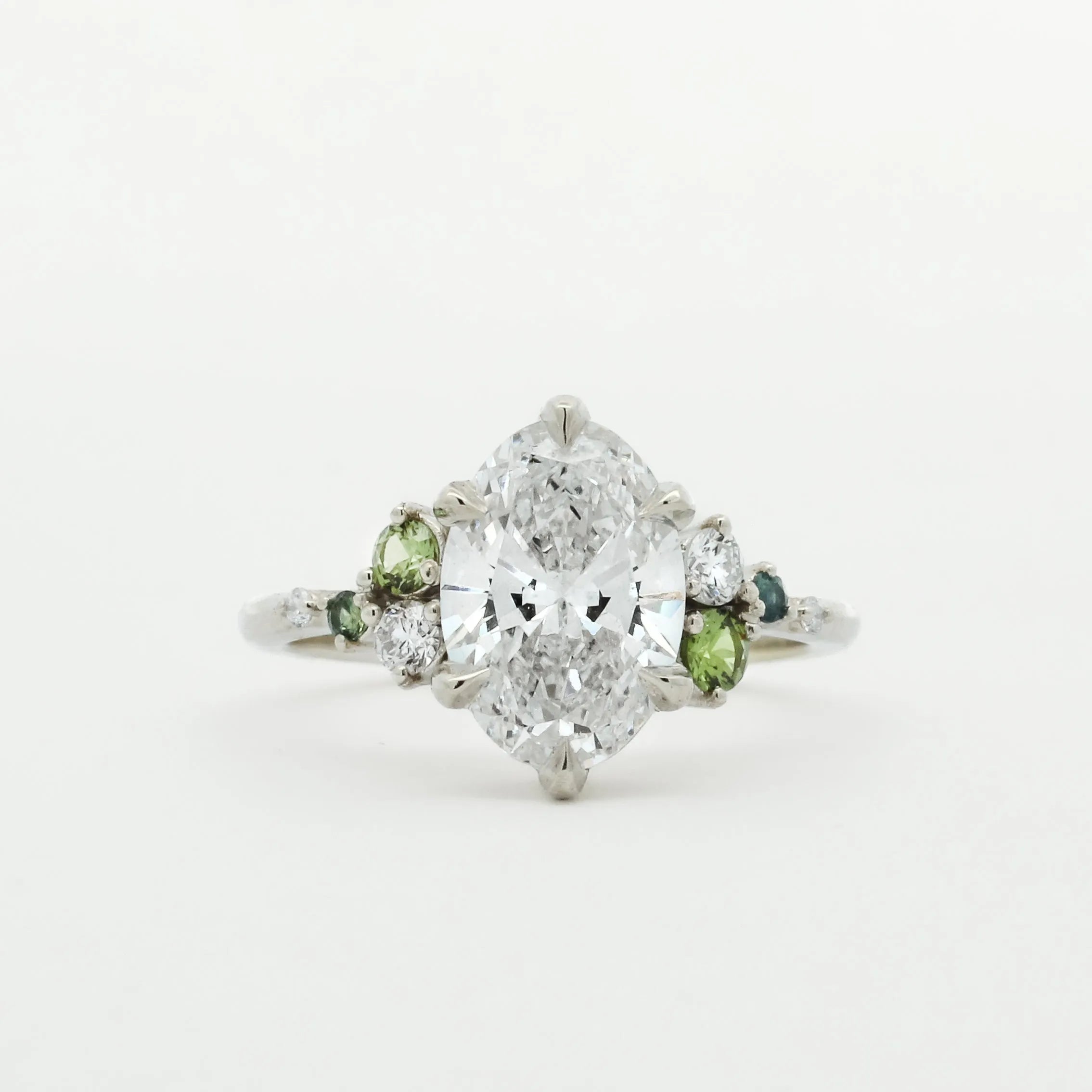Diamond ring with small green sapphires on a white background
