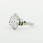 Diamond ring with green gemstones on a white background