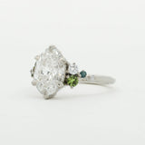 Diamond ring with green gemstones on a white background