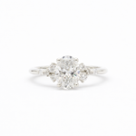 diamond engagement ring in white gold with large oval diamond and smaller scattered round diamonds on a white background