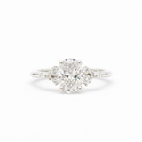 diamond engagement ring in white gold with large oval diamond and smaller scattered round diamonds on a white background