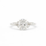 diamond engagement ring in white gold with large oval diamond and smaller scattered round diamonds on a white background