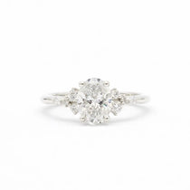 diamond engagement ring in white gold with large oval diamond and smaller scattered round diamonds on a white background
