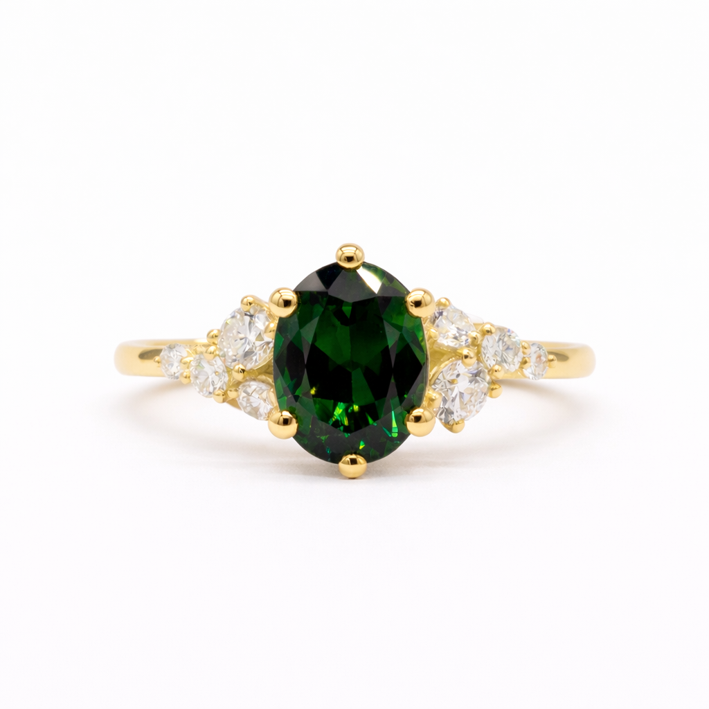Gold ring with a green gemstone and leaf-like diamond accents on a white background