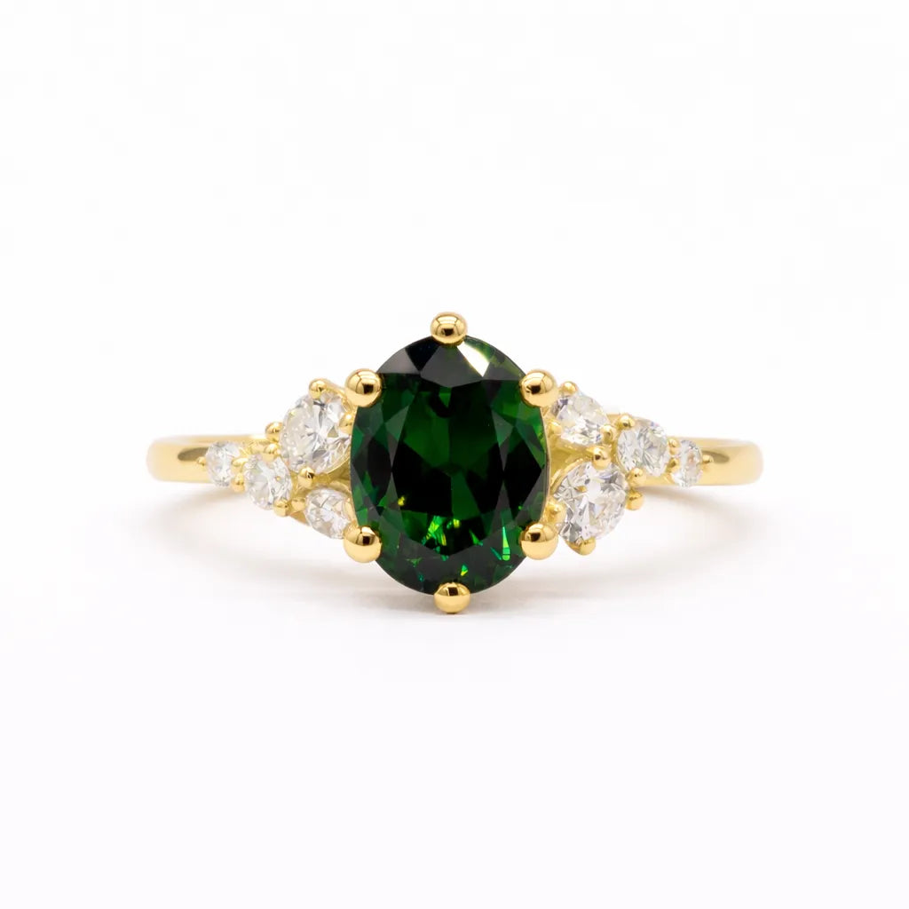 Gold ring with a green gemstone and leaf-like diamond accents on a white background