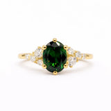 Gold ring with a green gemstone and leaf-like diamond accents on a white background