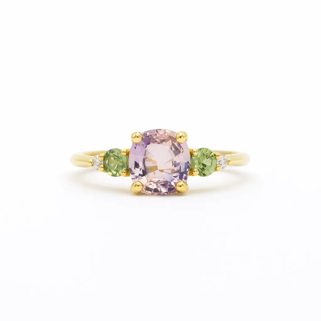 pink sapphire engagement ring with round green sapphires and diamonds on a white background