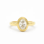 chunky gold engagement with a double bezel oval diamond on a white background