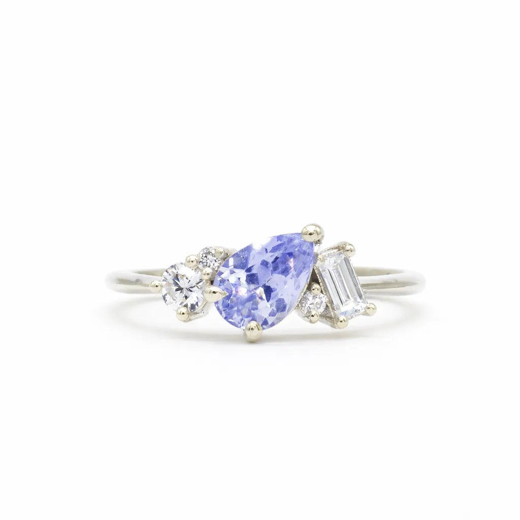 white gold engagement ring with cornflower blue pear sapphire and round and baguette shaped accent diamonds on a white background