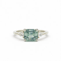 light blue sapphire engagement ring with trilliant diamonds in white gold on a white background