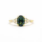 blue green oval sapphire engagement ring with 6 accent stones on a white background