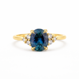 Gold ring with a blue gemstone and smaller diamonds on a white background