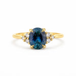 Gold ring with a blue gemstone and smaller diamonds on a white background