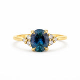 Gold ring with a blue gemstone and smaller diamonds on a white background