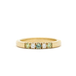 Gold ring with embedded green and white gemstones on a white background
