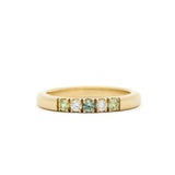 Gold ring with embedded green and white gemstones on a white background