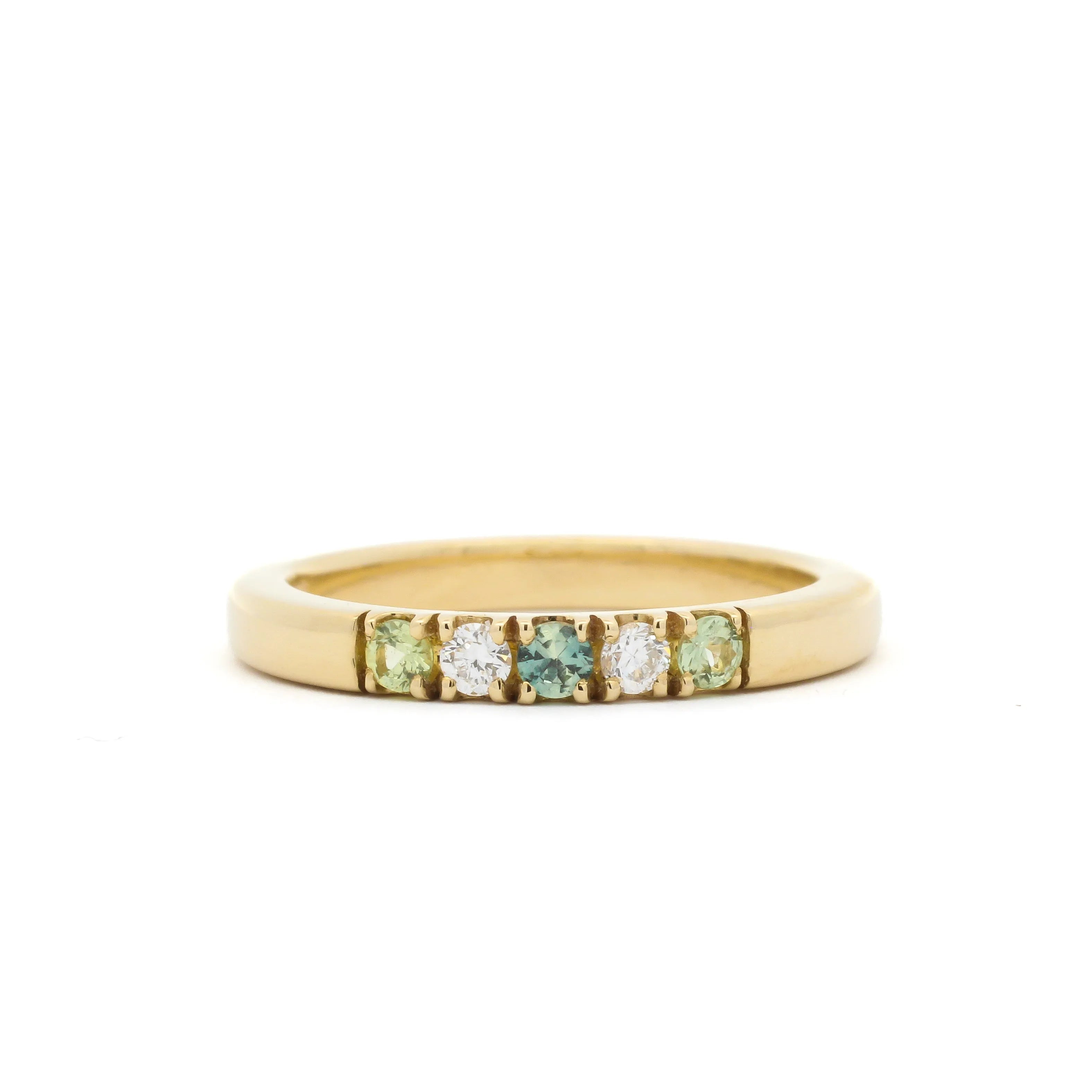 Gold ring with embedded green and white gemstones on a white background