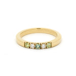 Gold ring with green gemstones on a white background