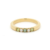 Gold ring with green gemstones on a white background